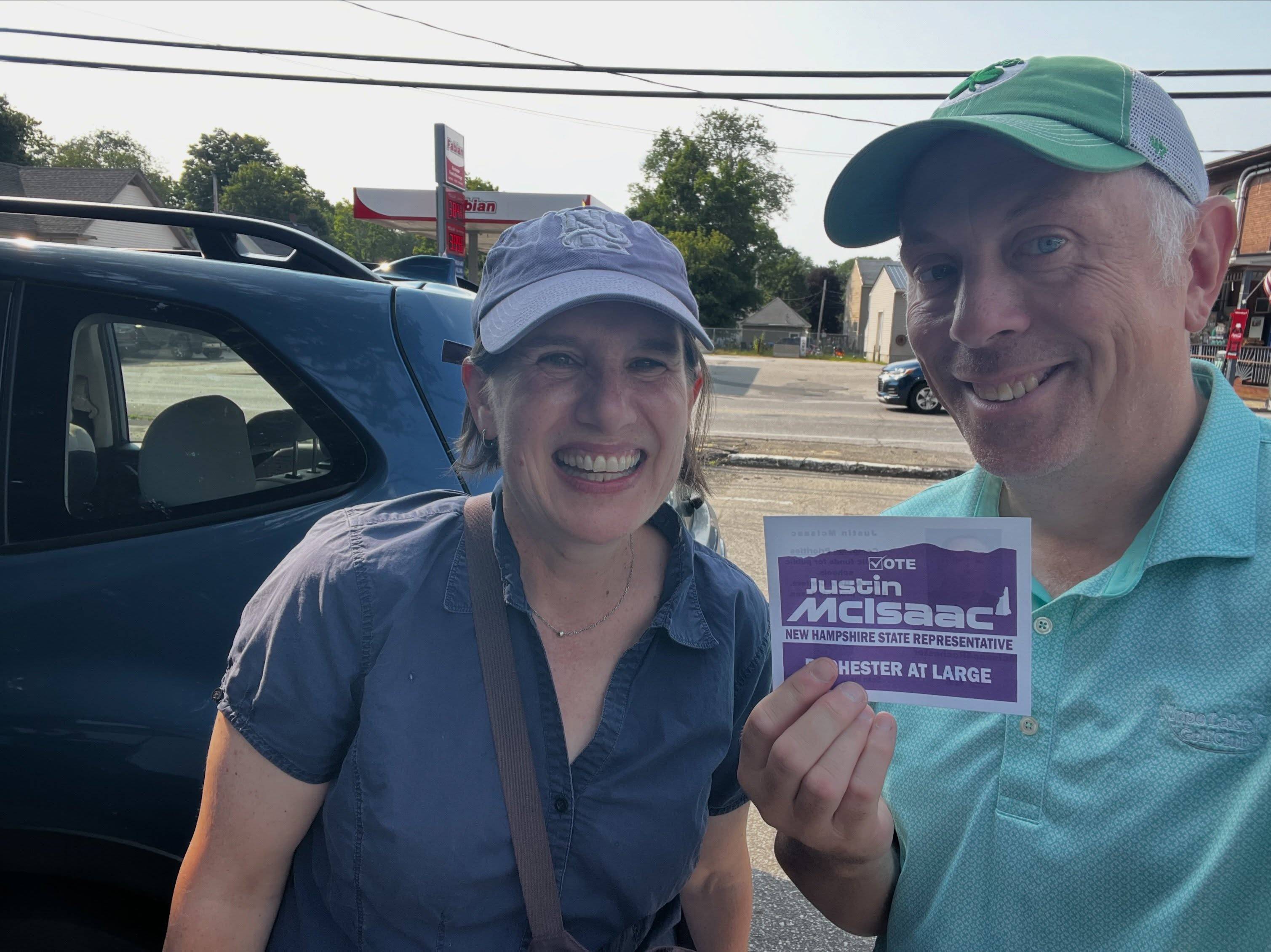Justin McIsaac and volunteer Alexis Simpson holding a campaign card while knocking on doors in East Rochester